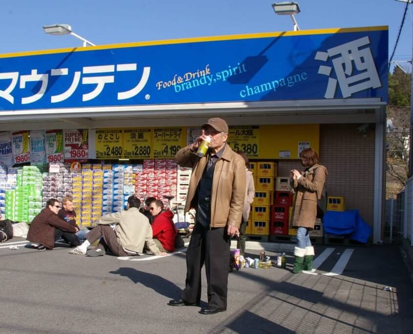 People Enjoying a Drink Outside a Liquor Store During a Festival